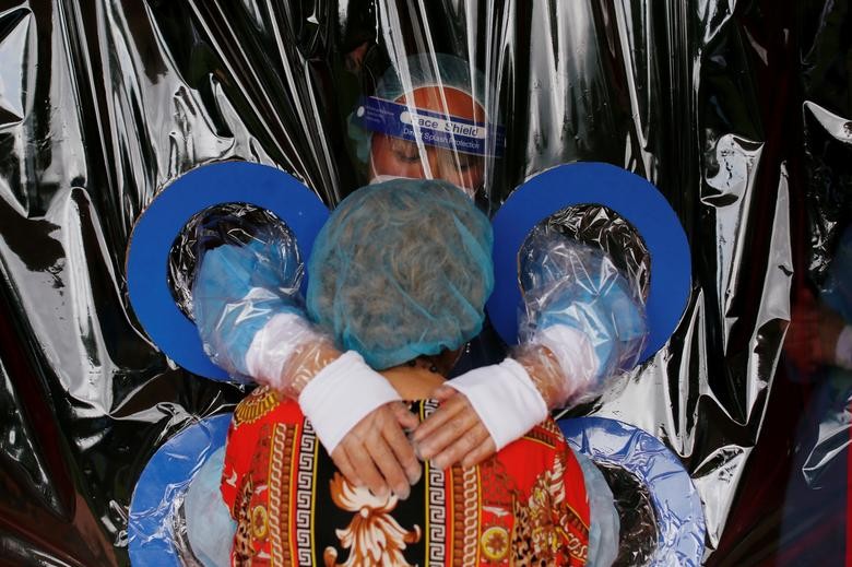 Arcelia Aguilar, a resident of "Hogar Jardin De Los Abuelitos", receives a hug from her niece Maria Aguilar through "El muro de los Abrazos" (The Wall of Hugs) which is a wall made from plastic sheets to protect against the coronavirus, in San Salvador, El Salvador September 1, 2020. REUTERS/Jose Cabezas